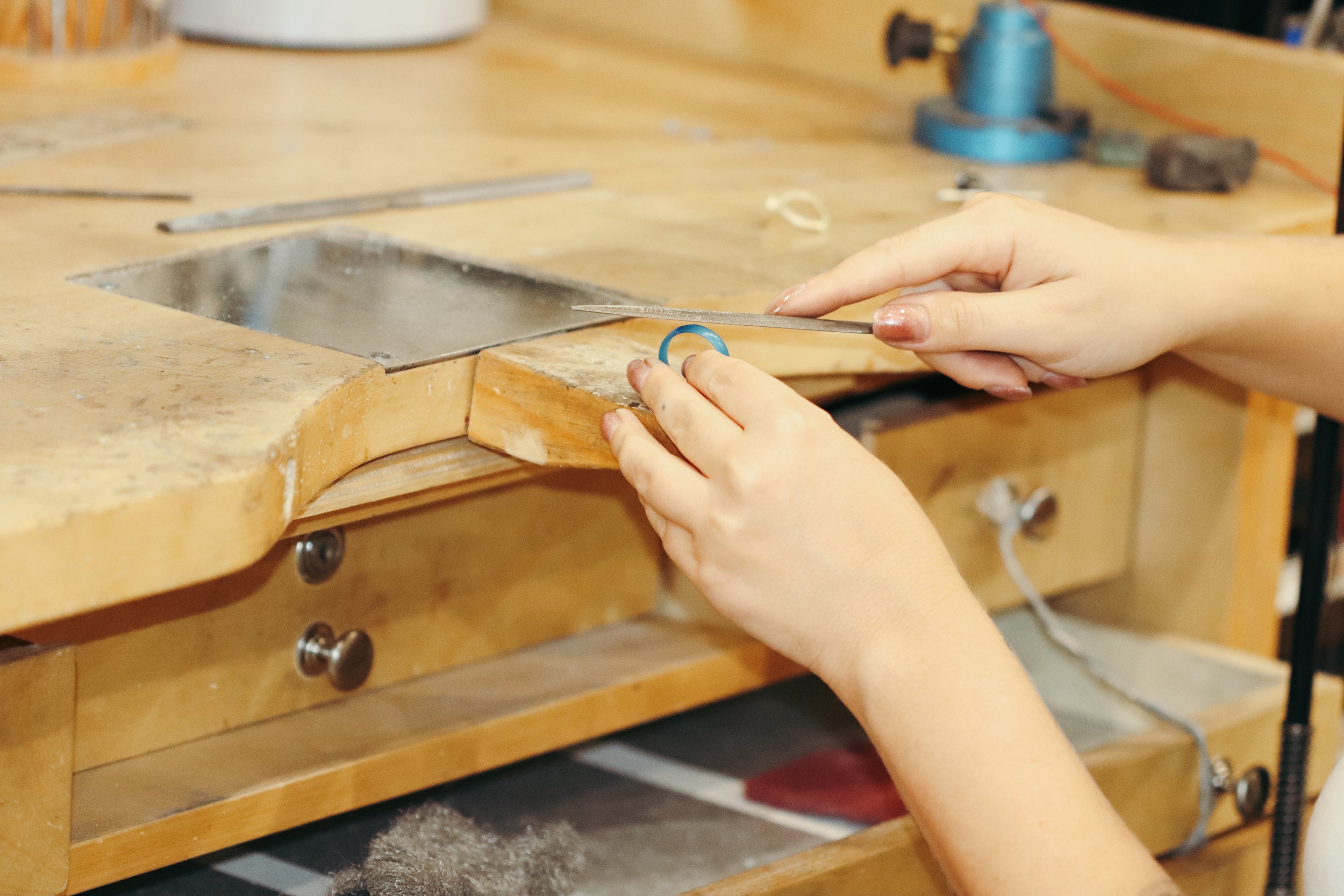 Jeweler working on shaping a wax carving at a bench