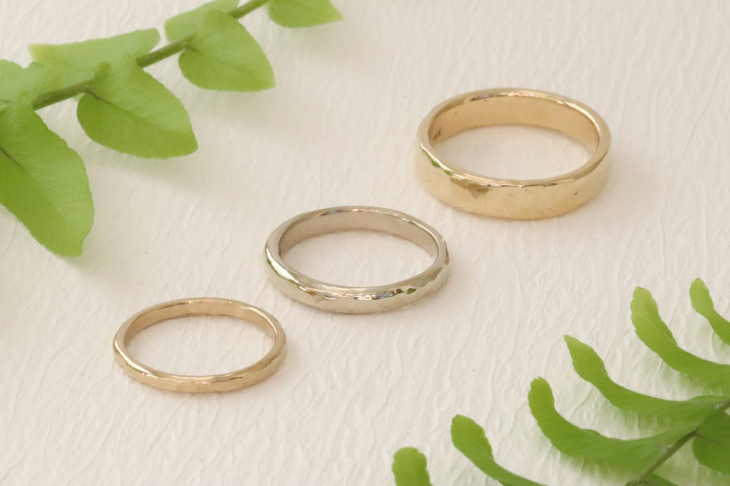 Front lifestyle view of 2mm Hammered Band in 14k yellow gold, 3mm Hammered Band in 14k white gold, and 4.5mm Hammered Band in 14k yellow gold Front lifestyle view of 2mm Hammered Band in 14k yellow gold, 3mm Hammered Band in 14k white gold, and 4.5mm Hammered Band in 14k yellow gold