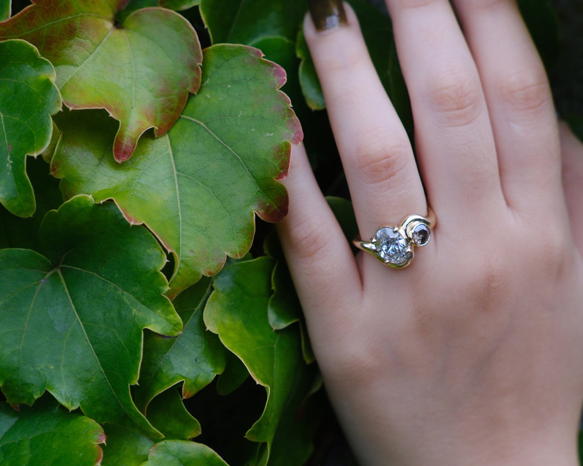 Model wears Dip Toi et Moi Ring by Kestrel Dillon Jewelry on ring finger over a natural green plant backdrop